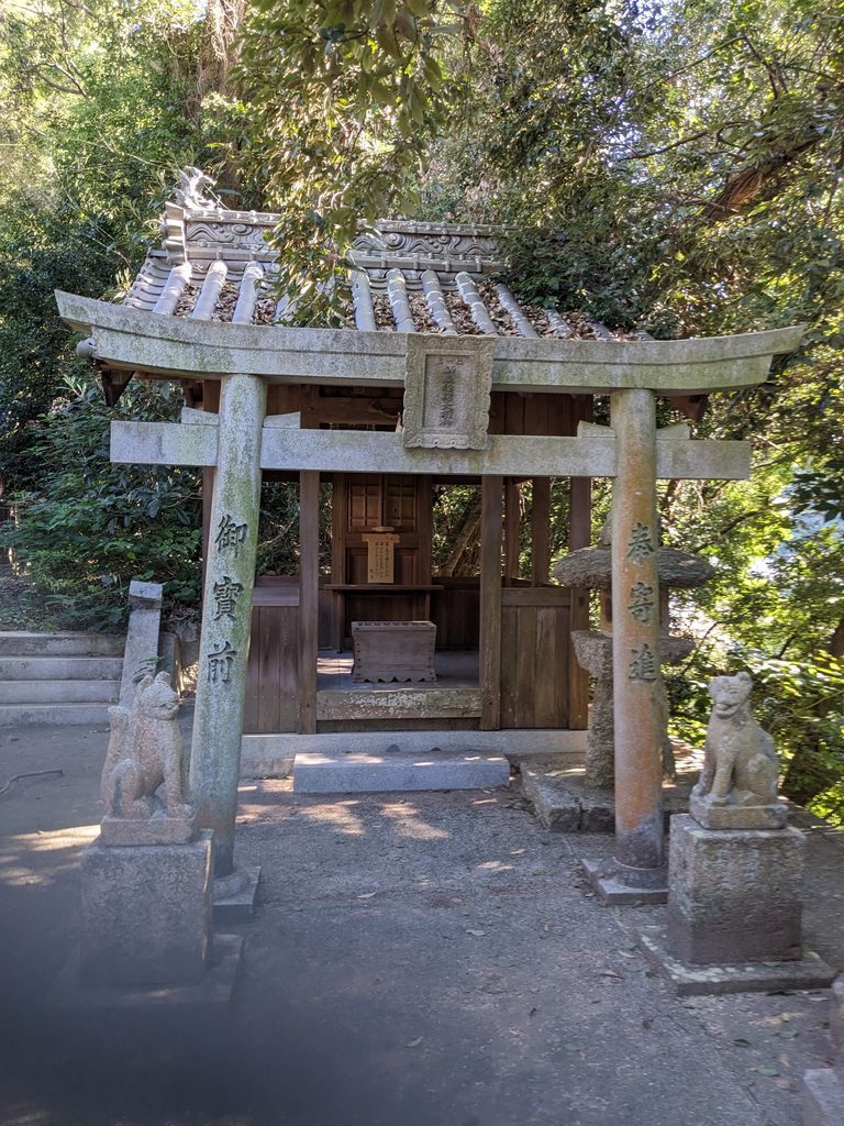 境内の小社の正面に立つ石鳥居と左右の石像