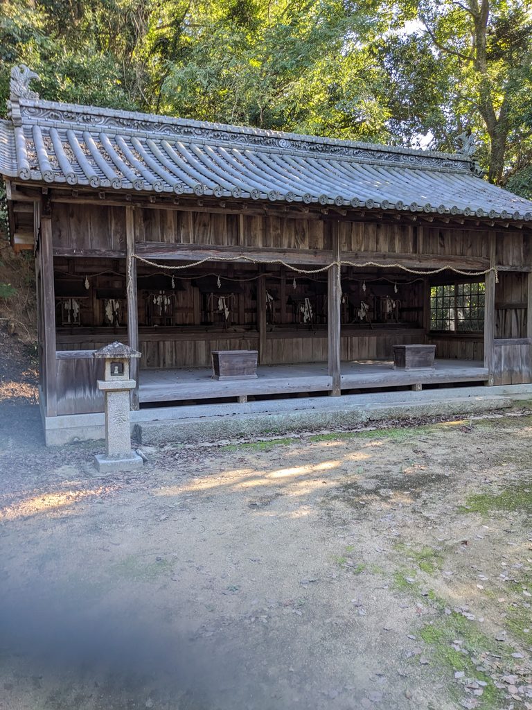 真名井神社の境内にある瓦屋根の建物と内部に並ぶ小さな祠