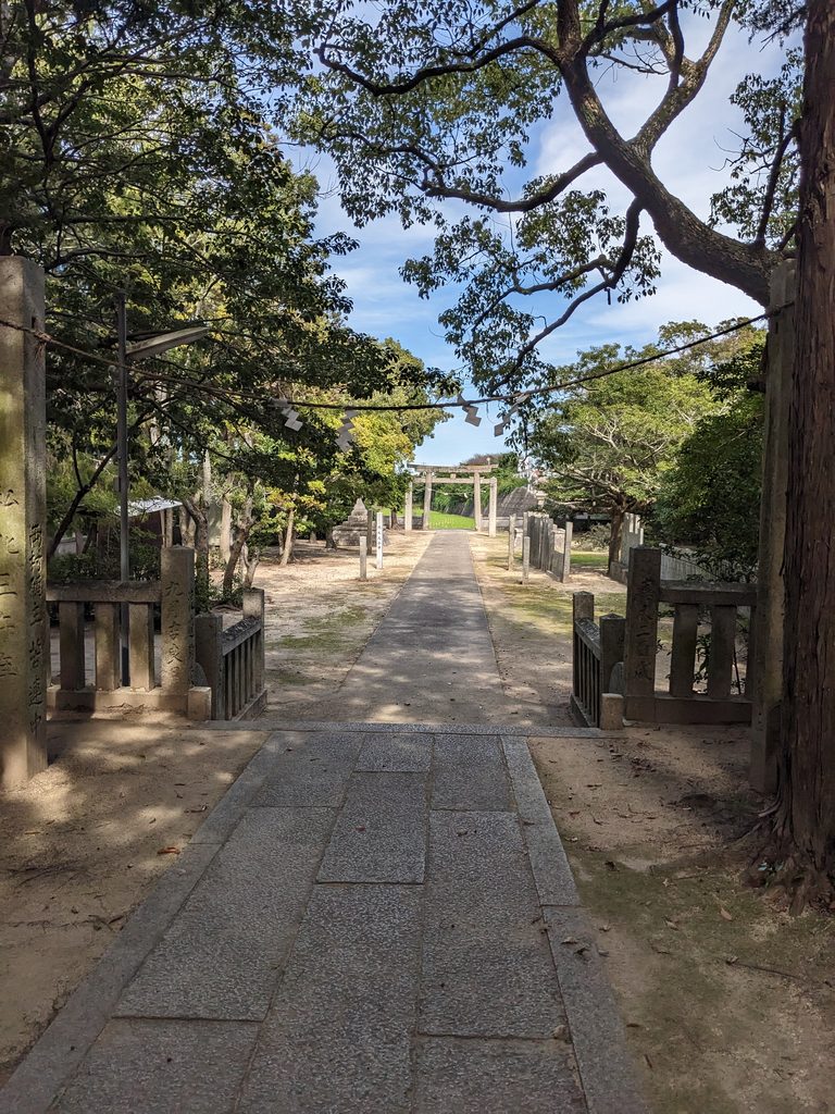 三嶋神社・上徳の境内から石柱越しに見た、遠くの鳥居へ続く参道